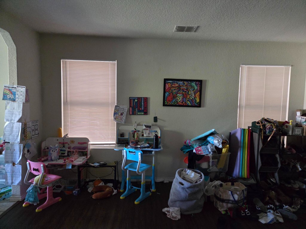 Open living room wall with two kids homework desks and clutter along the floor