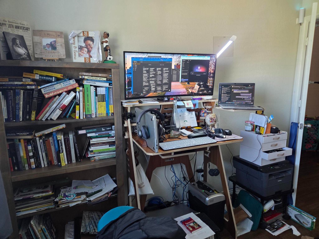 Standing desk, bookshelf, printer, and cables in our second bedroom and office space